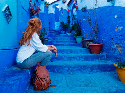 Kvinna sittande på trappan i den blå staden Chefchaouen, Marocko