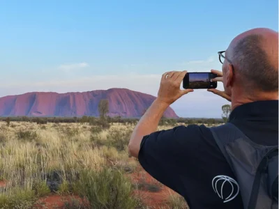 Man tar ett foto med mobiltelefonen av Uluru i Australien