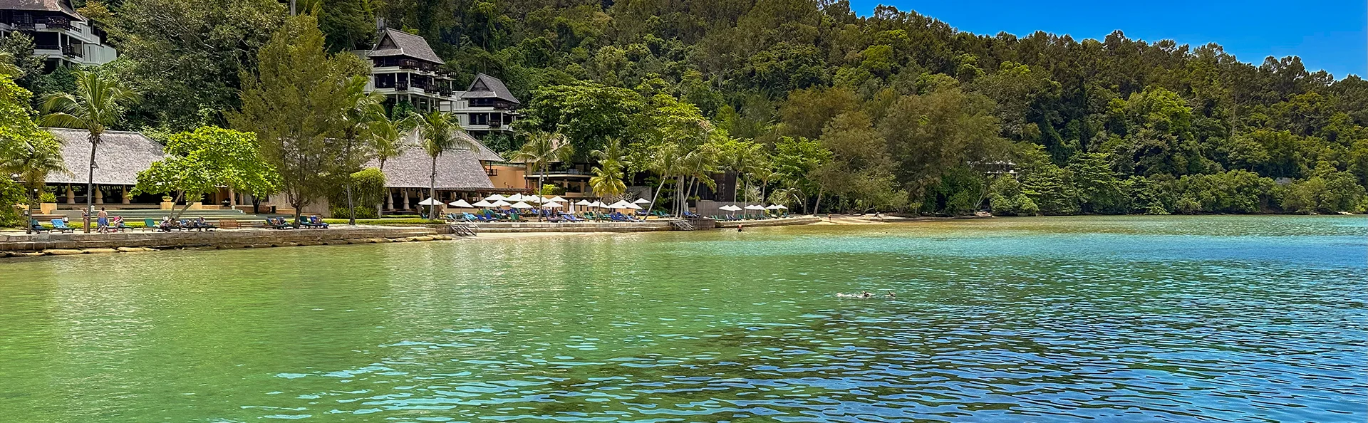 Lugn lagun med resort, palmer och gröna kullar