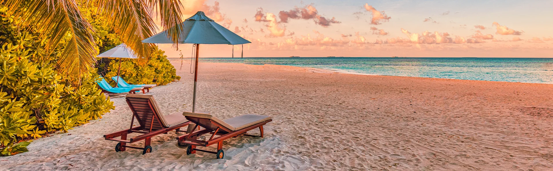 Solstolar på en tropisk strand på Mauritius i solnedgången