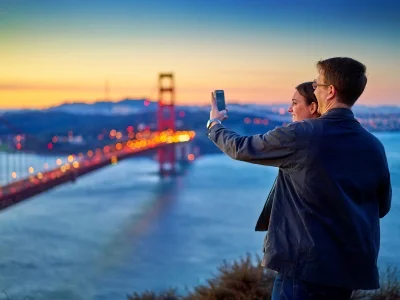 Man och kvinna tar en bild av Golden Gate-bron vid solnedgången
