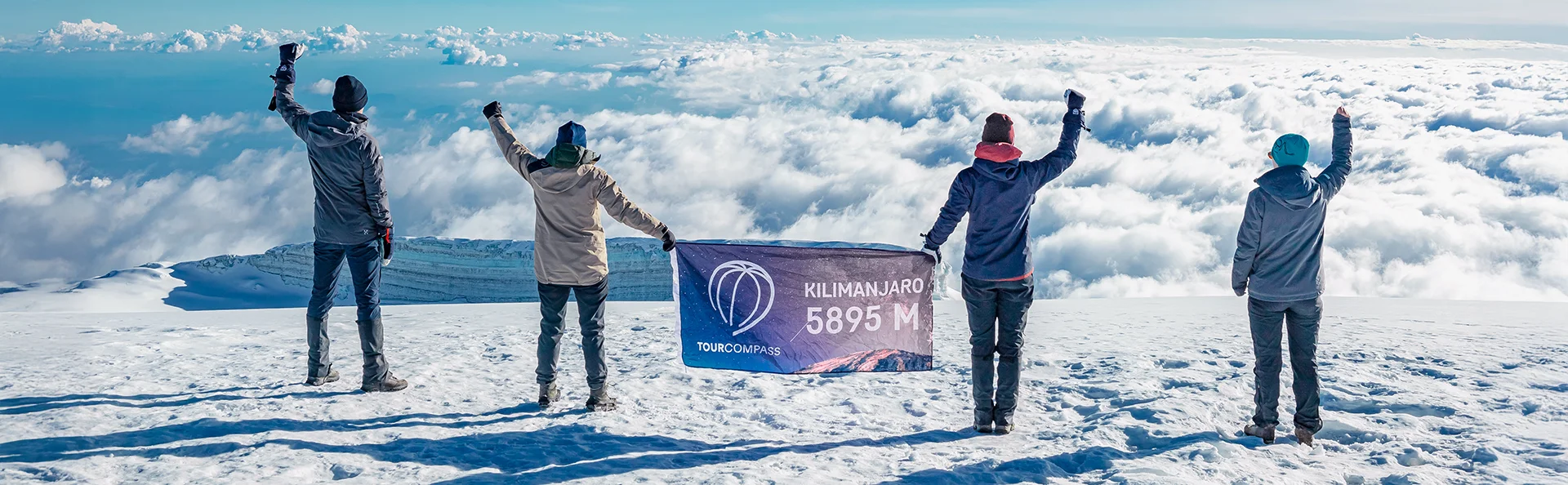 Grupp står med TourCompass-banner på toppen av Kilimanjaro