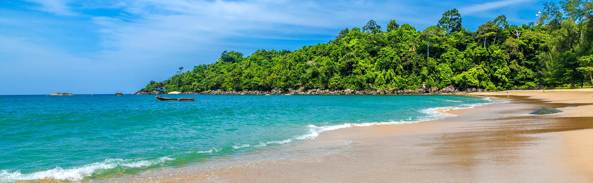 Tropisk strand i Thailand med turkost hav, mjuk sand och grönskande djungel i bakgrunden.