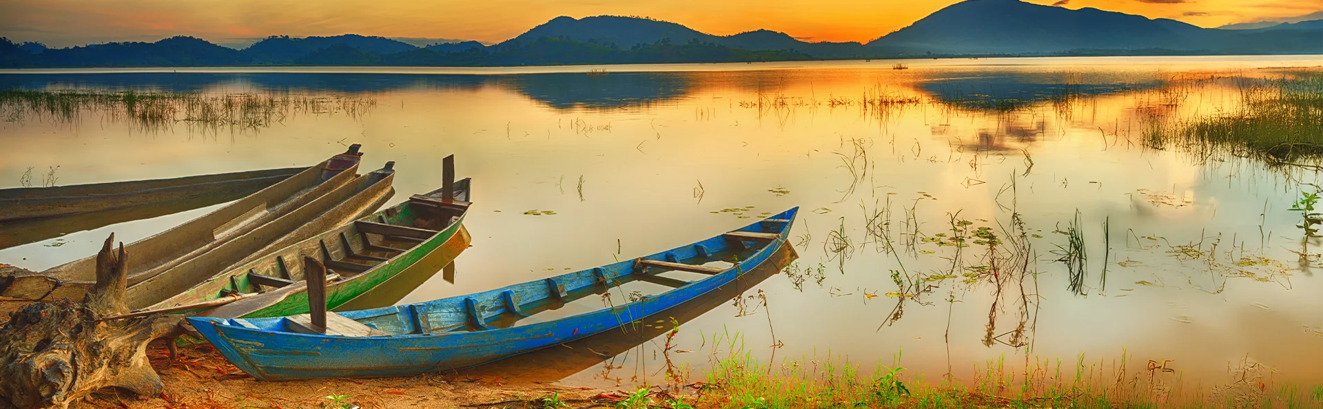 Träbåtar vid stranden av Lak Lake i solnedgångens sken i Vietnam