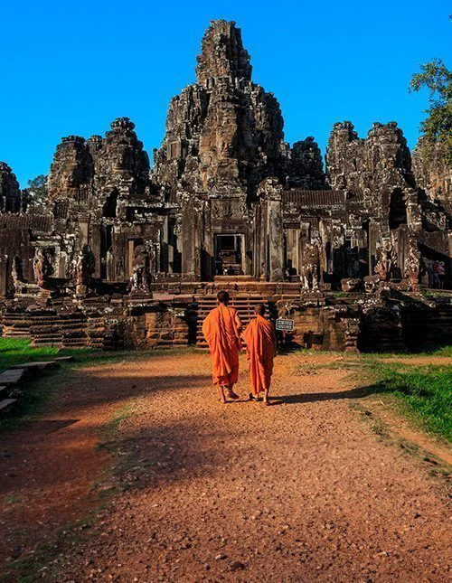 Munkarna bland Bayontemplets uråldriga stenansikten, Angkor, Kambodja