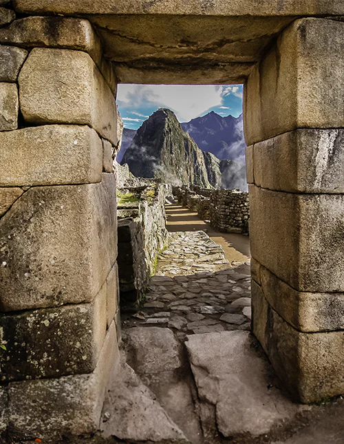 Stenportal med utsikt över Machu Picchu och de dimhöljda Anderna.